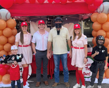 Adults and kids dressed in baseball attire at a fair booth